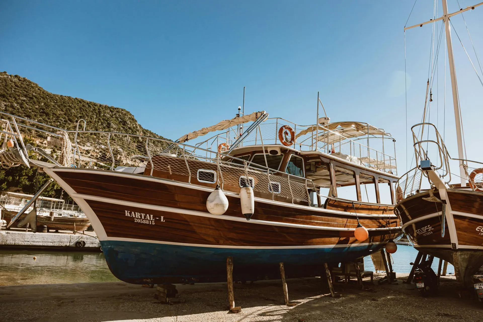Wooden boats hauled out on stands in a boatyard for hull and bottom work.